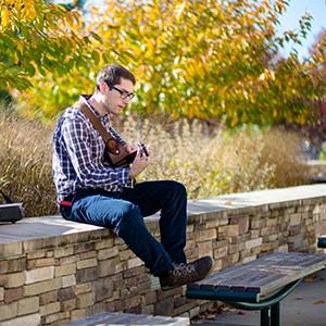 Male student playing guitar outdoors